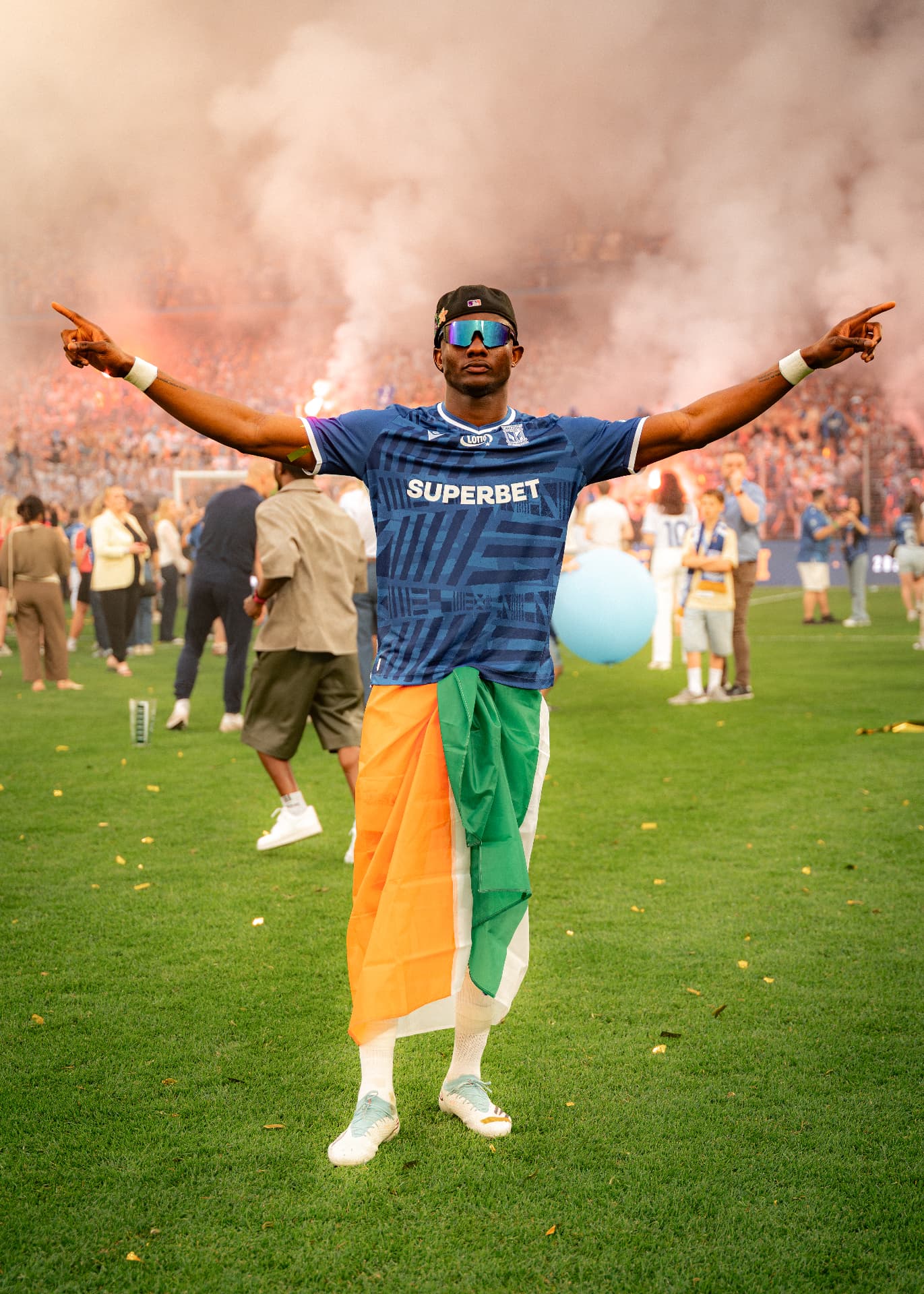 Yannick Agnero celebrating with the Ivorian flag amid stadium flares